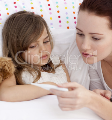 Portrait of mother taking her daughter's temperature