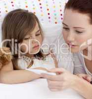 Portrait of mother taking her daughter's temperature