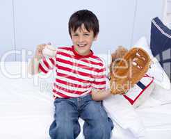 Happy little boy playing baseball in bed