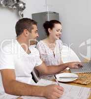 Couple working with a laptop in kitchen