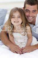 Portrait of smiling father and daughter in bed