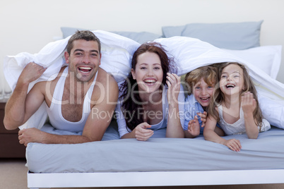 Young family playing in bed together