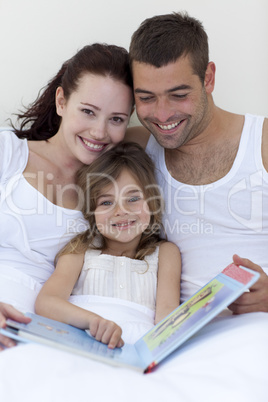 Parents and daughter reading in bed