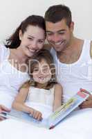 Parents and daughter reading in bed