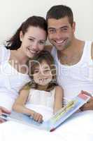 Portrait of parents and daughter reading in bed