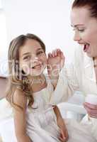 Happy mother putting cream on her daughter's face