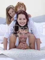 Portrait of happy parents and children having fun in bed