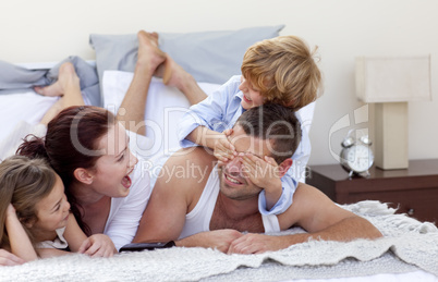 Happy young family having fun in bed