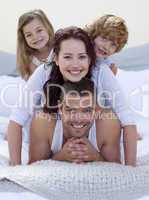 Portrait of happy family having fun in bed