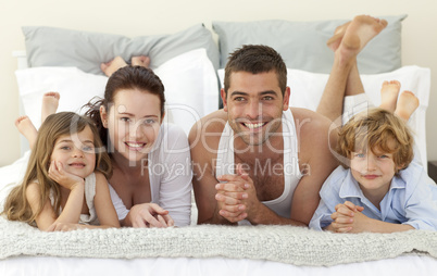 Portrait of happy family lying in bed