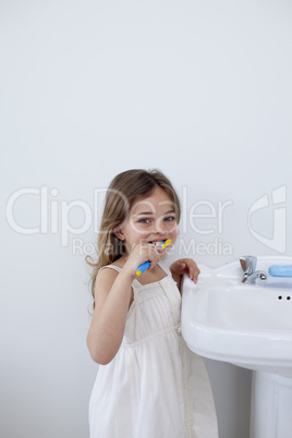 Little girl cleaning her teeth in bathroom with copy-space