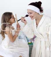 Mother applying blusher with her daughter