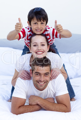 Happy parents and son in bed with thumbs up