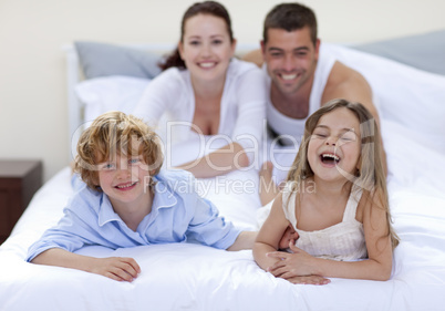 Brother and sister having fun in bed with their parents