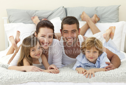 Happy family lying in bed and smiling at the camera