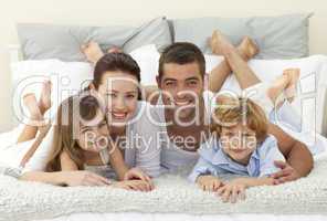 Happy family lying in bed and smiling at the camera