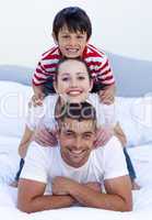 Happy parents and son playing in bed