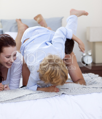 Son playing with his parents in bed