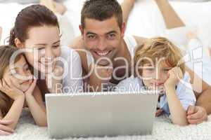 Parents and children in bed using a laptop