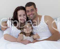 Happy young family in bed with thumbs up