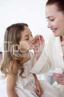 Mother putting cream on her daughter's face