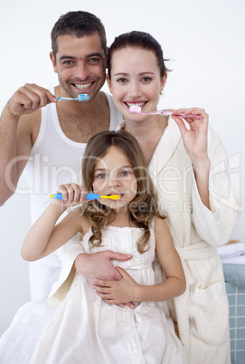 Parents and daughter cleaning their teeth in bathroom