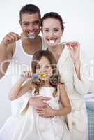 Parents and daughter cleaning their teeth in bathroom