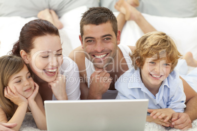 Family in bed having fun with a laptop