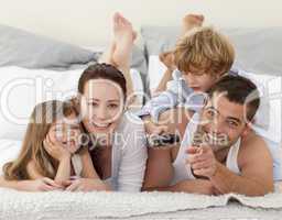 Family relaxing in bed and using a remote