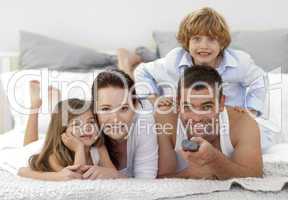 Family lying in bed and using a remote