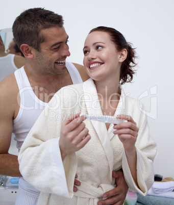 Happy couple in bathroom holding a pregnancy test