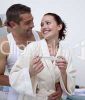 Happy couple in bathroom holding a pregnancy test