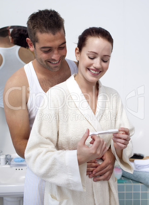 Happy couple in bathroom looking at pregnancy test
