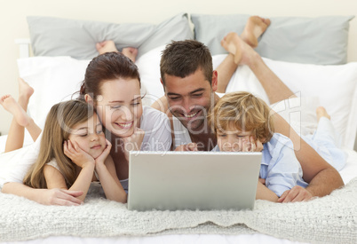 Family in bed using a laptop