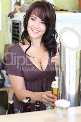 young brunette draws beer at the bar
