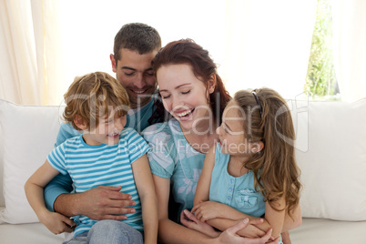Family sitting on sofa having fun