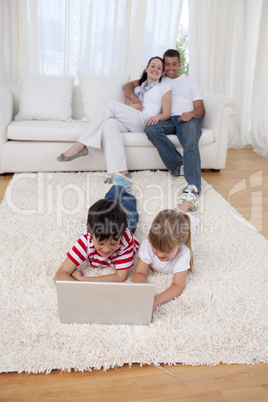 Brother and sister using a laptop on floor in living-room