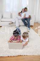 Brother and sister using a laptop on floor in living-room
