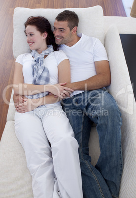 Couple lying on sofa watching television
