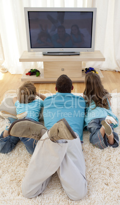 Family on floor in living-room watching television