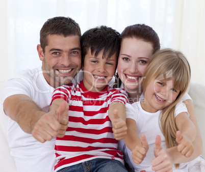 Family sitting on sofa with thumbs up