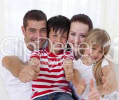 Family sitting on sofa with thumbs up