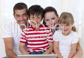 Smiling family at home using a laptop