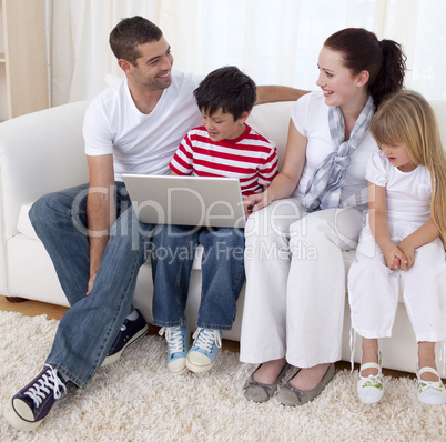 Smiling family in living-room using a laptop