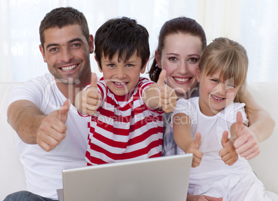 Family at home using a laptop with thumbs up