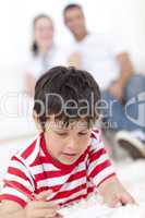 Smiling kid drawing on floor in living-room