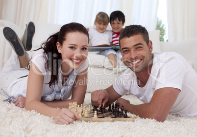 Happy couple playing chess on floor in living-room