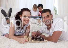 Happy couple playing chess on floor in living-room