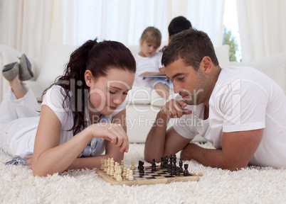 Parents playing chess on floor in living-room