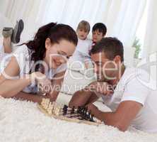 Smiling couple playing chess on floor in living-room